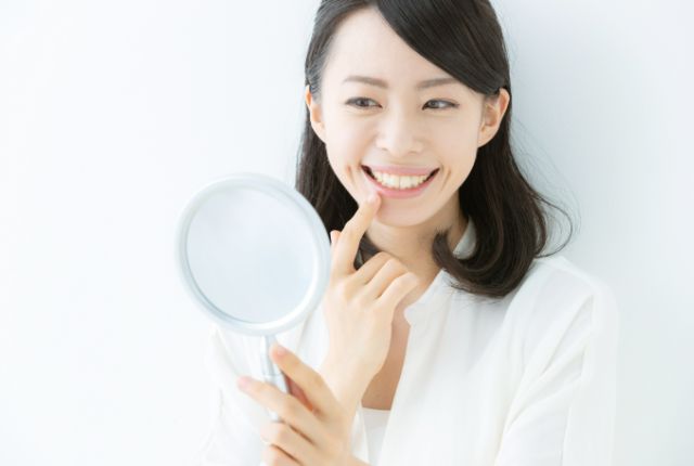 鏡で白い歯を見る女性