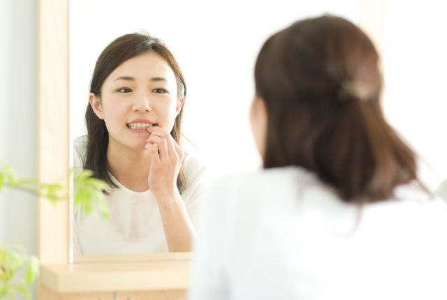 鏡で歯を見ている女性