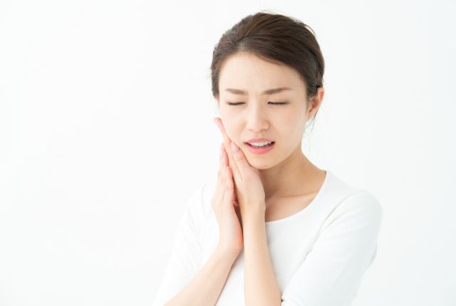 頬に手を当て痛そうにしている女性